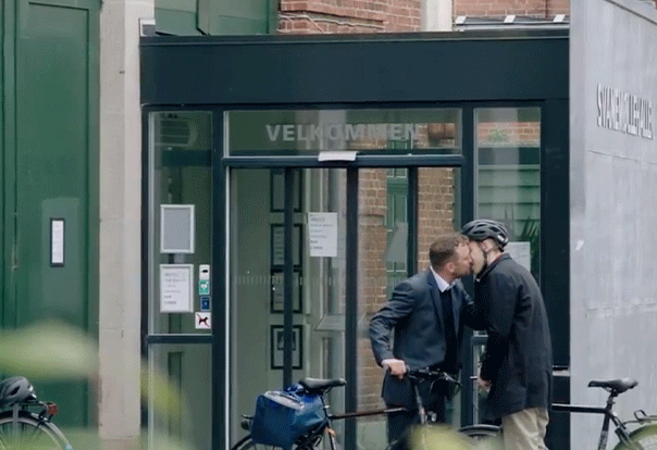 Two men kiss outside office building