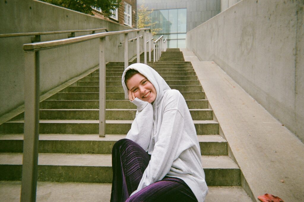 AURA-frivillig smiler på en trappe iført hættetrøje