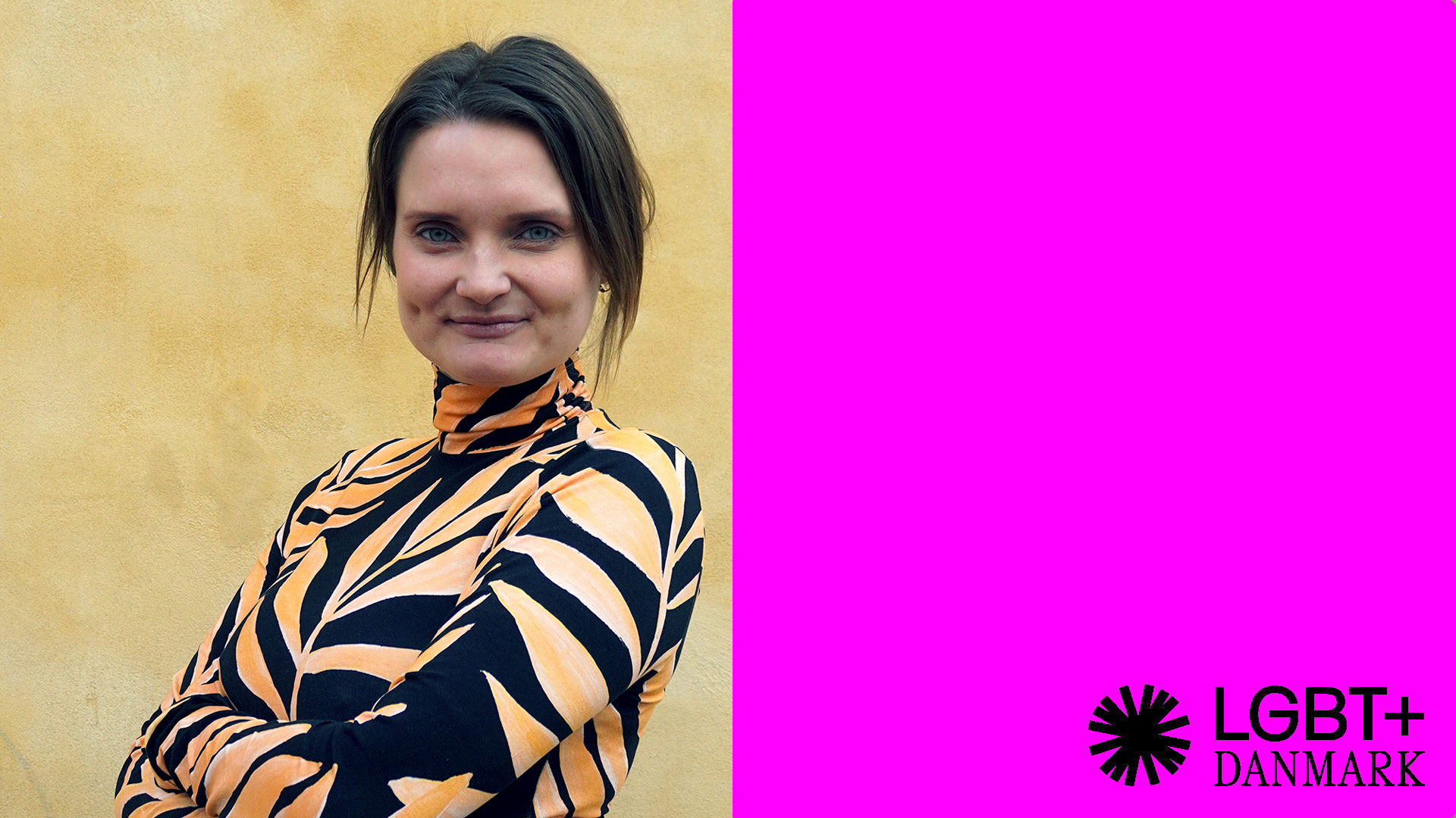 Foto af Mie Birk Jensen ved siden af pink firkant med LGBT+ Danmarks logo